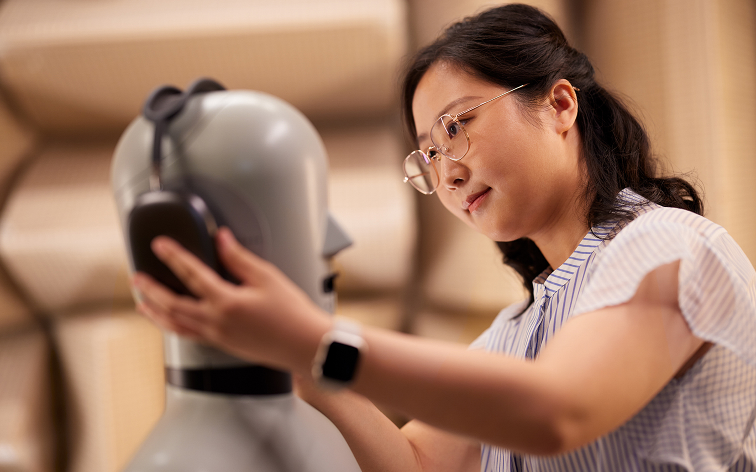 Una persona del equipo de Hardware de Apple acomodando unos AirPods Max en un maniquí de laboratorio.