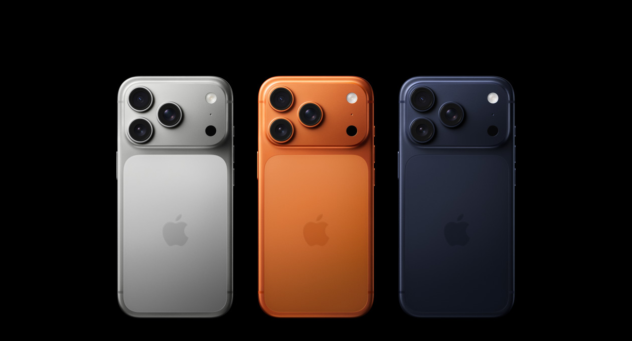 iPhone 17 Pro vist bagfra i alle tre farver, nemlig sølv, kosmisk orange og dybblå, med Pro Fusion-kamerasystem i øverste venstre hjørne, tre objektiver, mikrofon, blitz og Apple-logo i midten