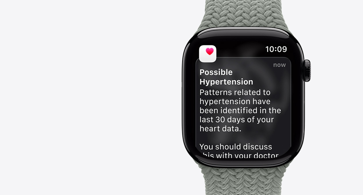 Apple Watch Series 11, natural color, titanium case, possible hypertension notification, pink heart in white box, right side exterior, Digital Crown, band, green gray Braided Solo Loop