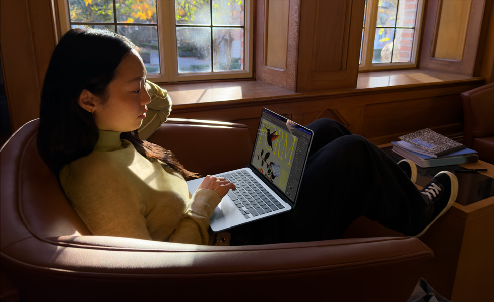 A person sitting in a chair using their MacBook Air