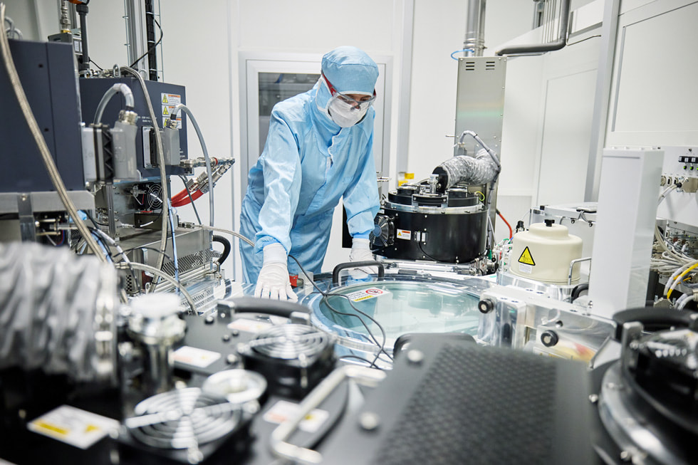 A worker wearing protective clothing examines equipment inside a lab-like setting at TRUMPF Ulm.