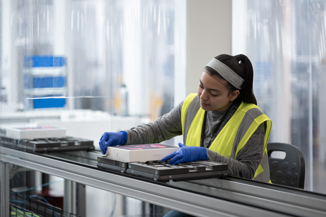 A worker on an assembly line works on product packaging.