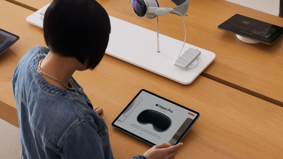 展示一位顧客在 Apple Store 零售店的 iPad 上查看 Apple Vision Pro。