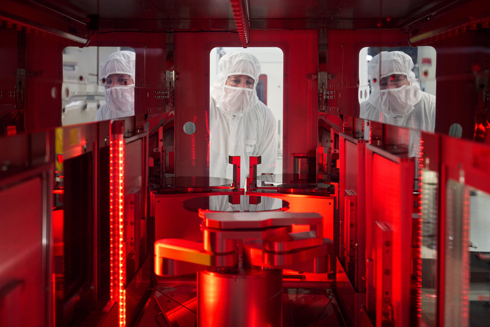 Three workers in protective clothing at Texas Instruments’ semiconductor wafer fabrication plant in Lehi, Utah.