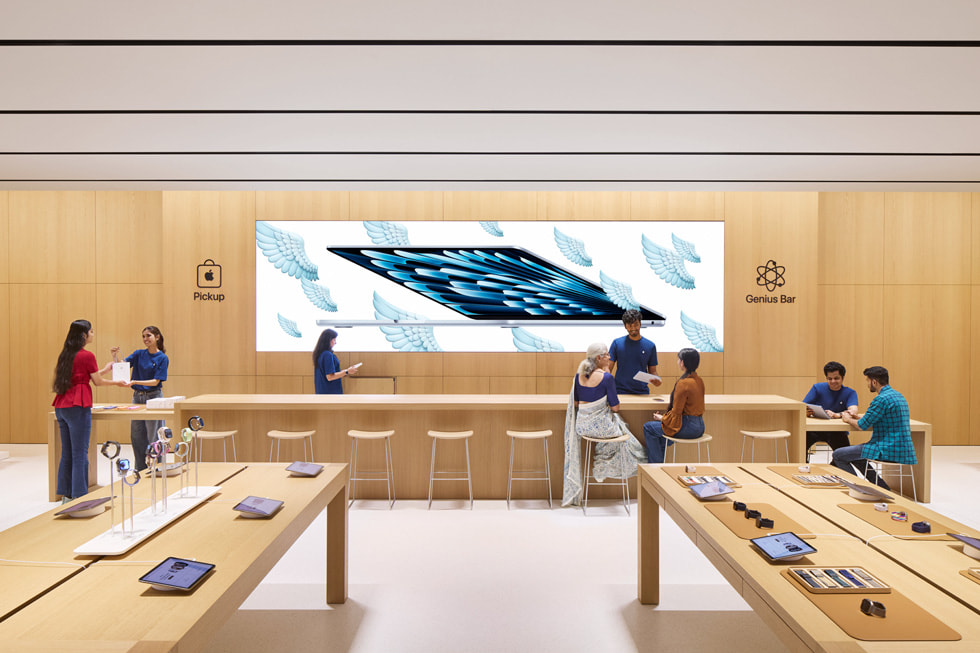 An image of Apple Specialists assisting customers at the Genius Bar and Apple Pickup area in Apple Hebbal.