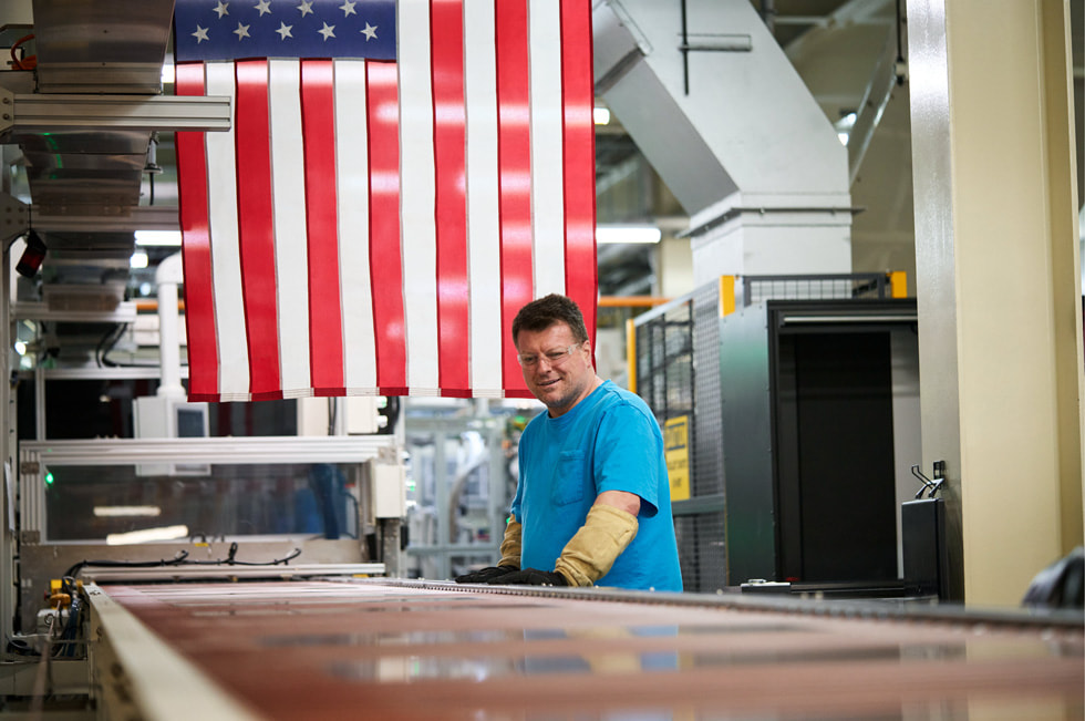 A worker at a conveyer belt inside a Corning glass facility.