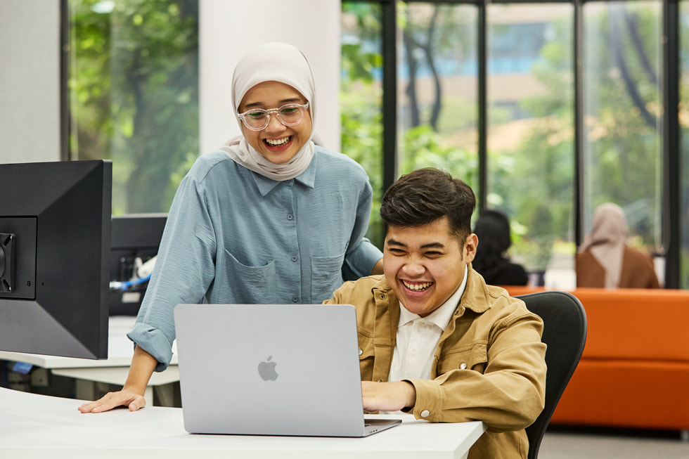 Dua orang duduk mengelilingi komputer MacBook di Apple Developer Academy di Indonesia