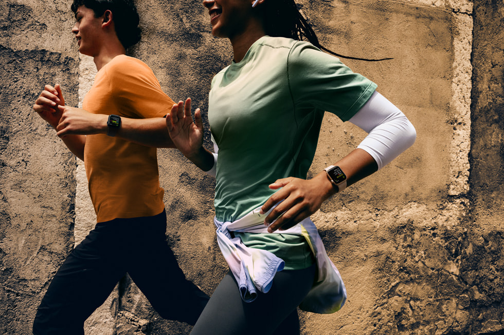 An image of two people running side by side while wearing Apple Watch SE 3 on their wrists.