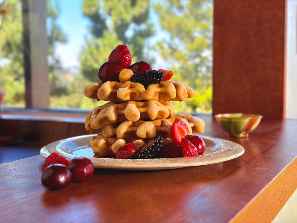A close-up photo of a stack of homemade waffles covered in colorful berries showing Focus Control on iPhone Air.