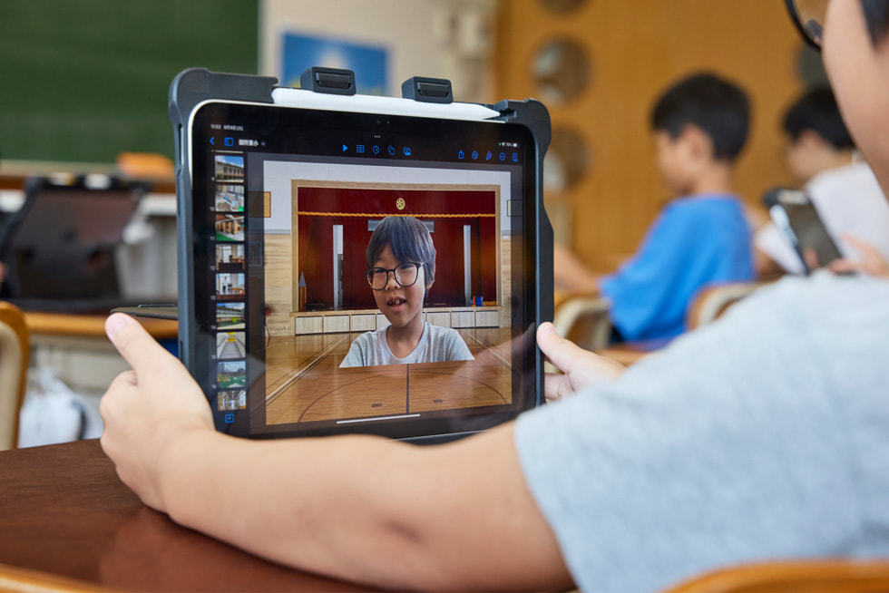 京都市の小学校の教室で、iPadを見ている子どもを肩越しに撮影した写真。上にタッチペンが置かれています。