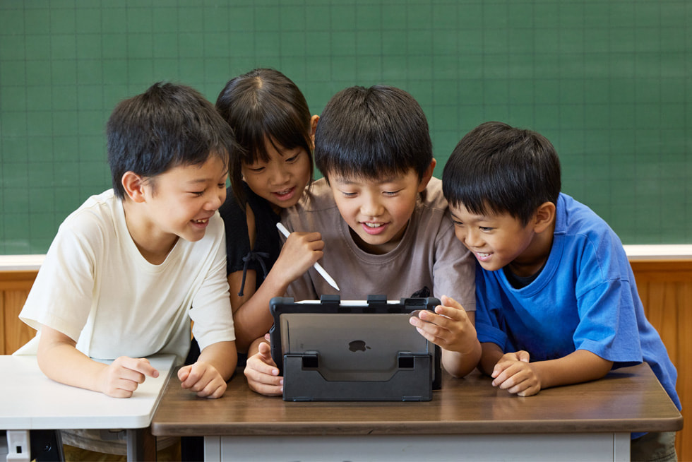 京都市の小学校の教室で、iPadとタッチペンを使って作業している4人の子ども。