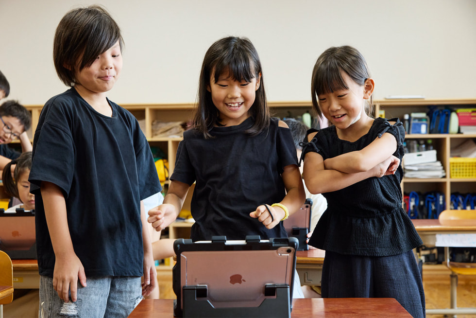 京都の小学校の教室で、iPadを見ている3人の子ども。