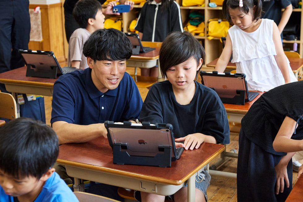京都市の小学校の教室で、iPadで作業している子どもをサポートする教師。
