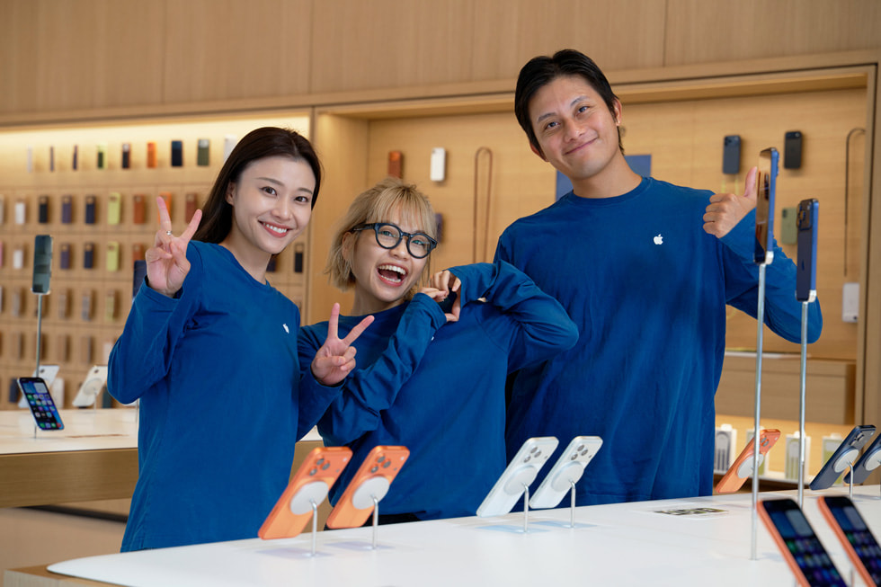 Three team members pose in front of an iPhone display at Apple Ginza.