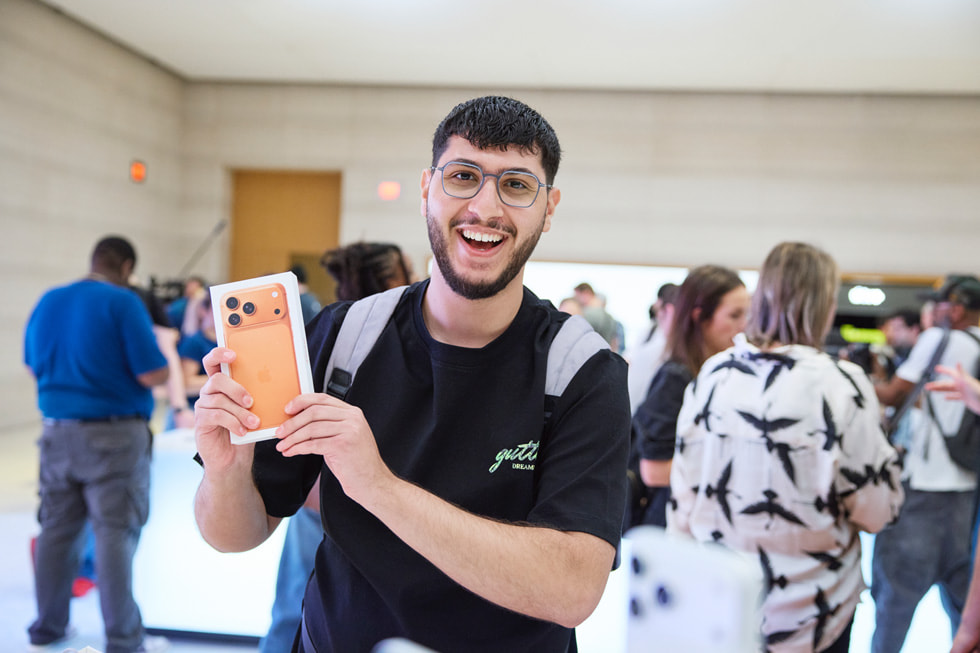 A customer shows off their new cosmic orange iPhone 17 Pro at Apple Fifth Avenue in New York.