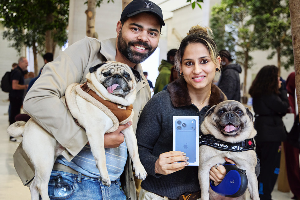 Two customers at Apple Regent Street in London hold their dogs while showing off their new deep blue iPhone 17 Pro. 
