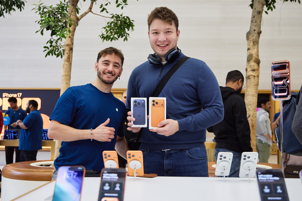 A customer celebrates their new deep blue and cosmic orange iPhone 17 Pro purchases with an Apple Regent Street team member. 