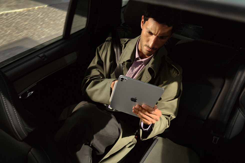 Un pasajero en el asiento trasero de un auto usa el nuevo iPad Pro con chip M5 mientras viaja.