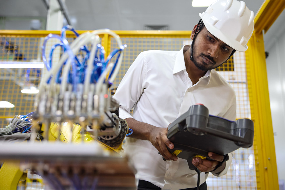 An employee looks at equipment at a supplier site in India.