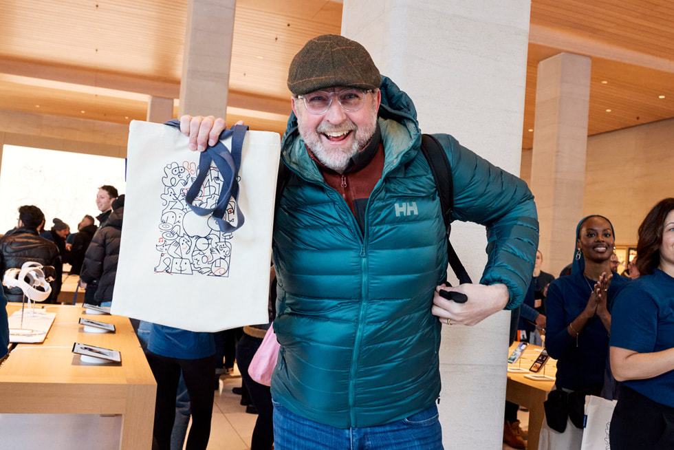 A customer holds up a bag featuring an illustration by Catherine Potvin.