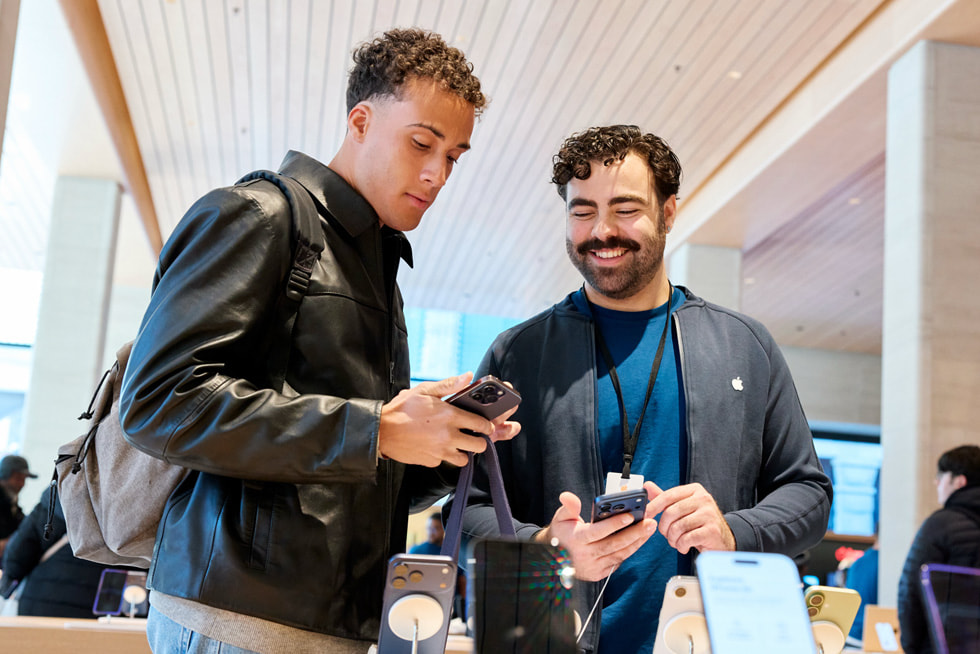 A customer talks to a team member next to the iPhone display at the new Apple Sainte-Catherine.