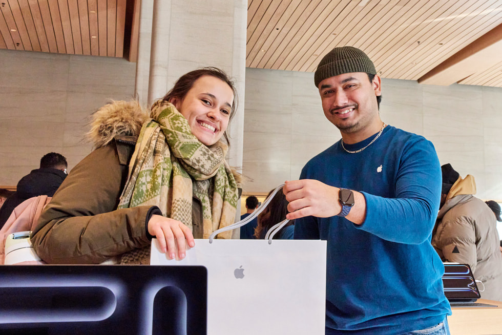 A customer holds up their new purchase at Apple Sainte-Catherine, as a team member looks on.