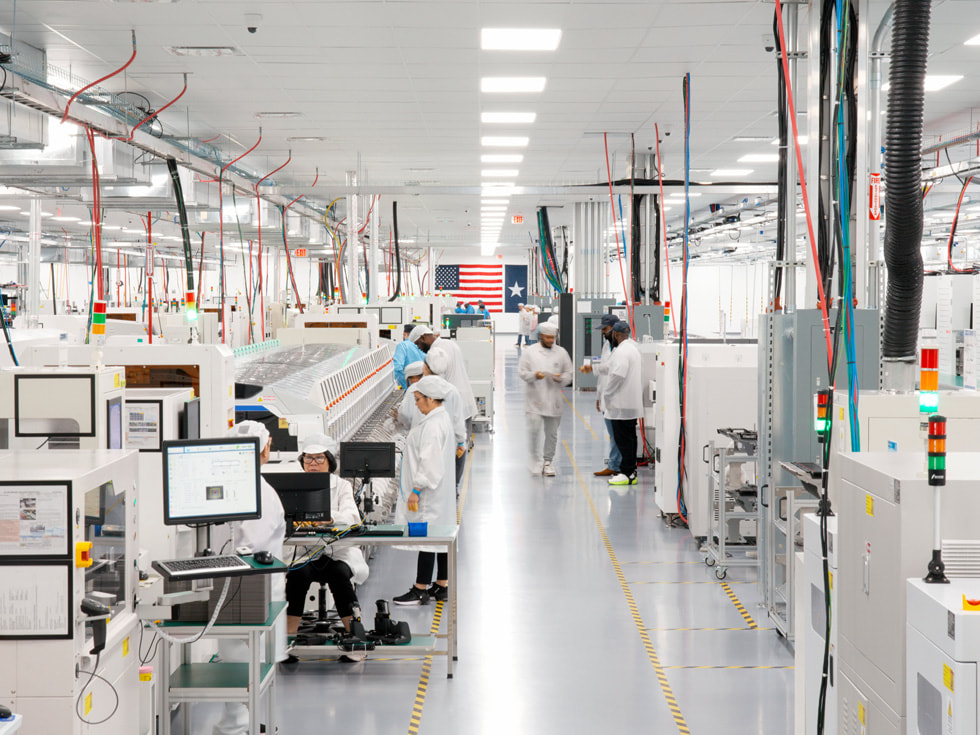 Technicians in protective clothing work on computers and other equipment in a Houston factory.