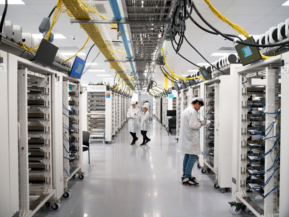 Technicians in protective clothing walk through the hallway of a Houston factory.