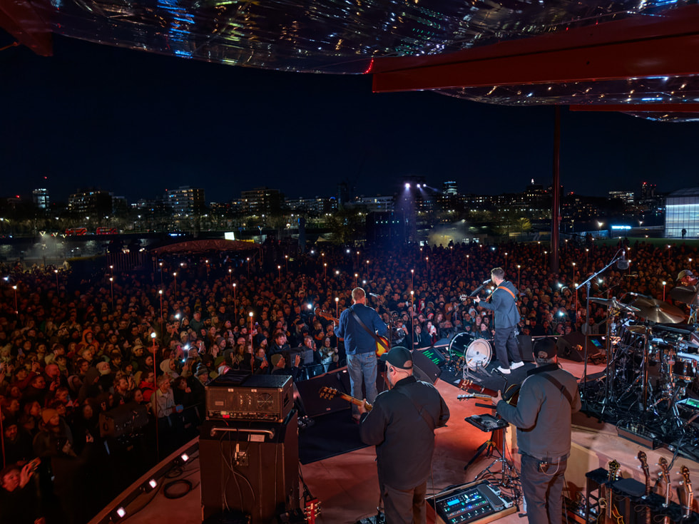 A view from the stage shows Mumford & Sons performing at Apple Battersea in London.