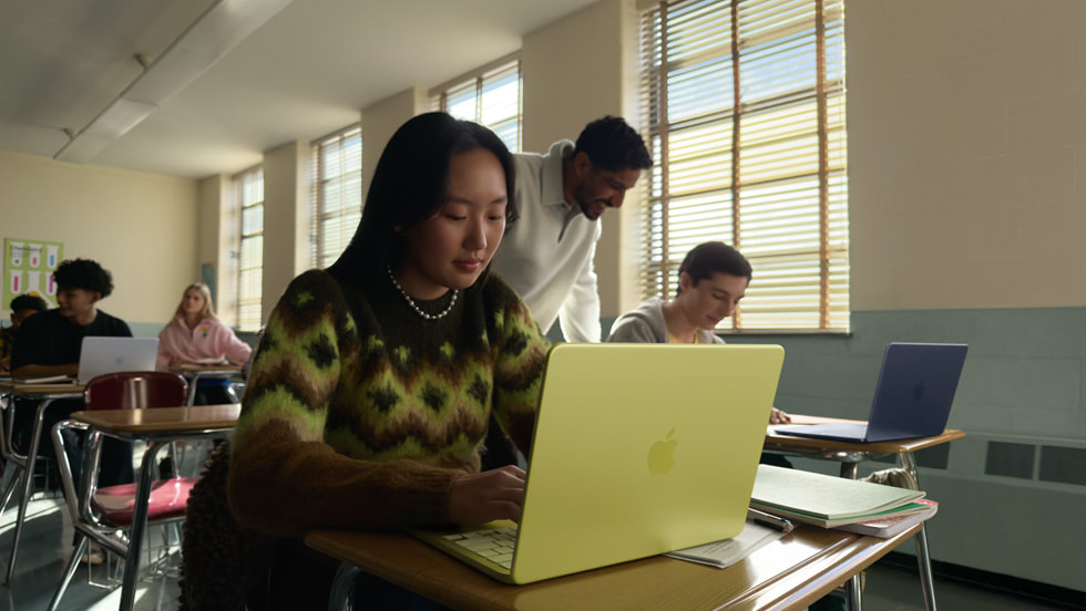 Una persona estudia con su MacBook Neo amarillo cítrico en un salón de clases.