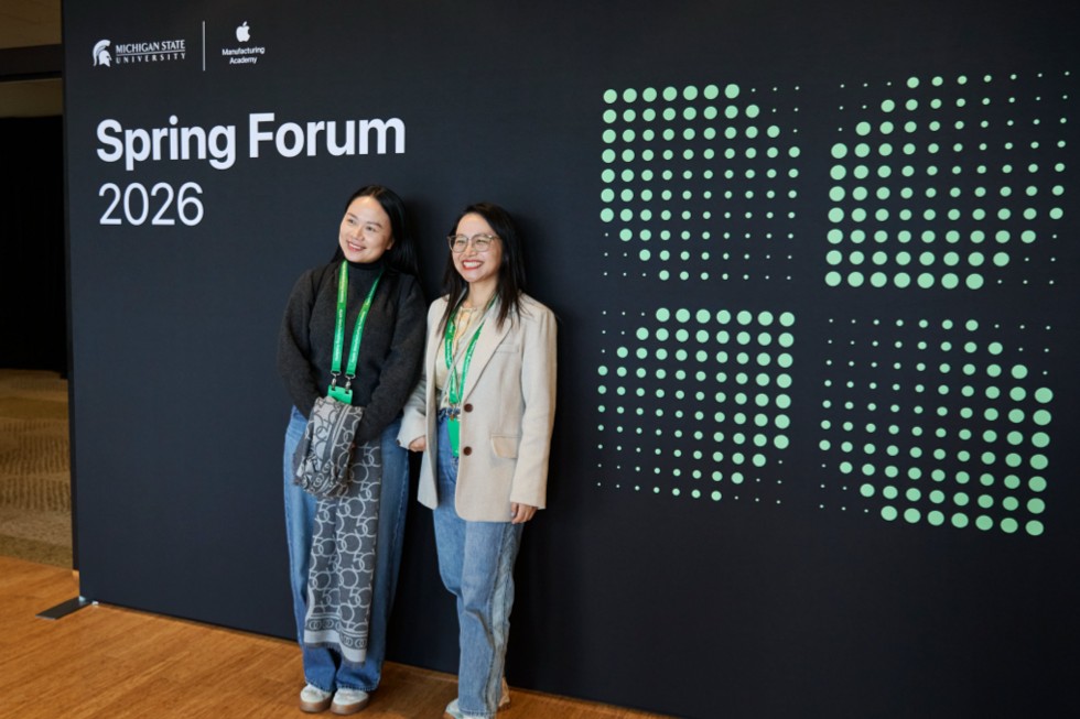 Dos participantes posan frente a un cartel que dice “Spring Forum 2026”.