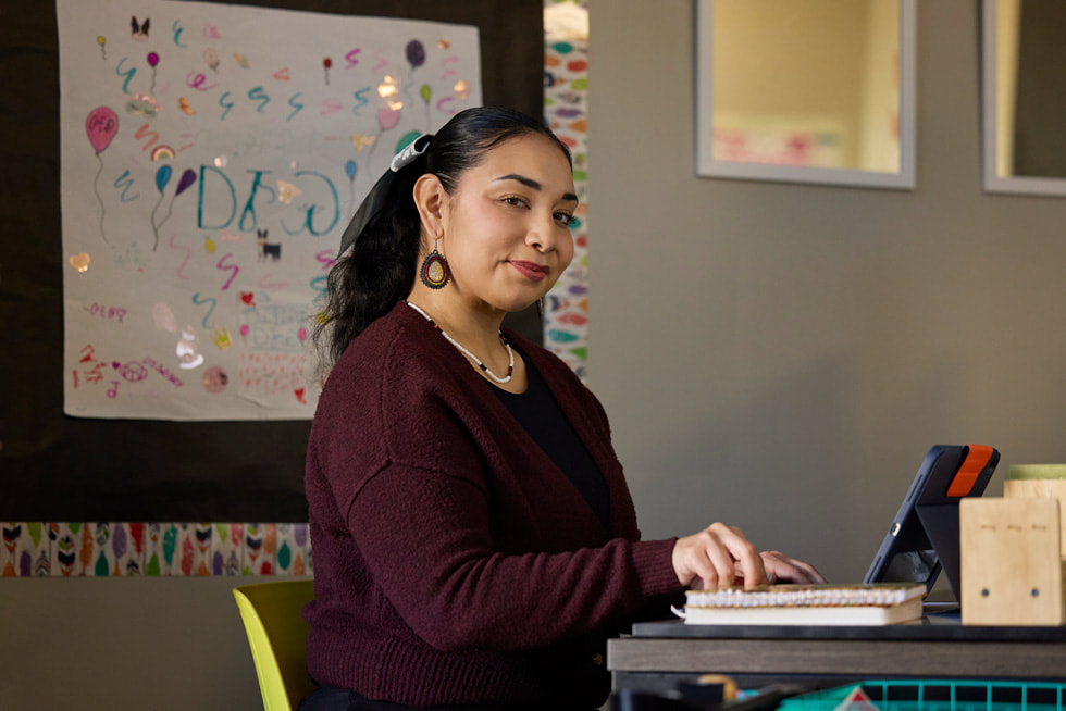Erlinda Soap is pictured in a classroom sitting at a desk with iPad.