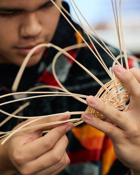 A student is shown practicing basket weaving.