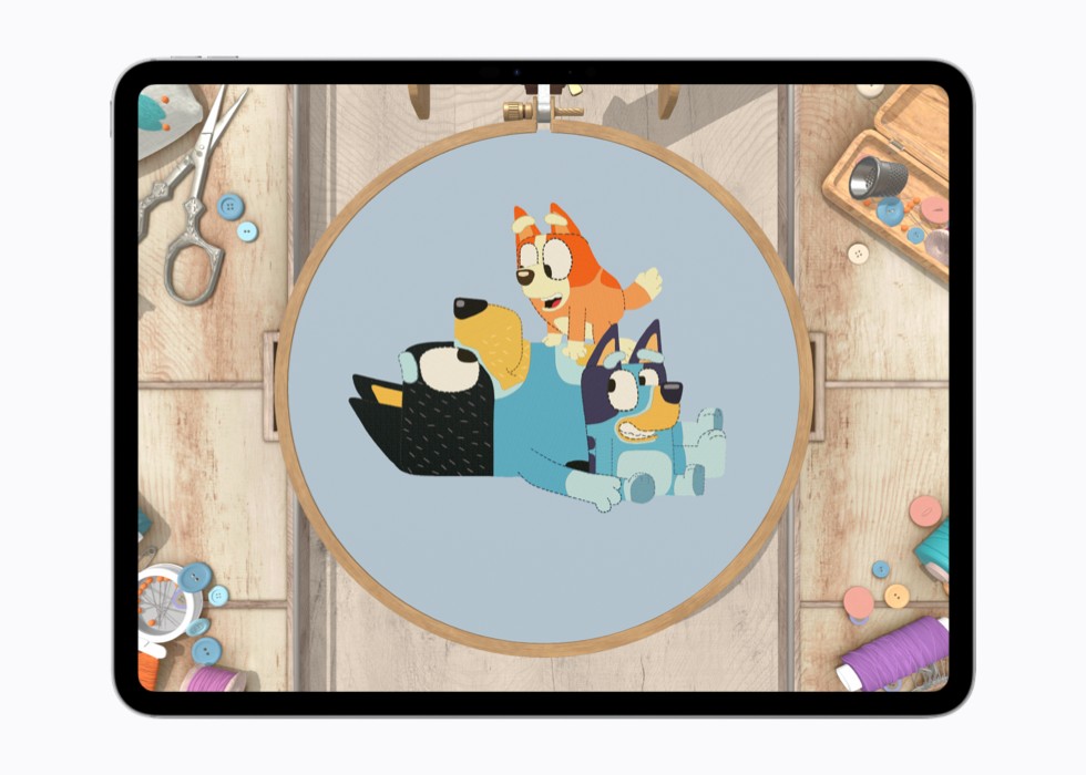 A still from the game stitch. shows a completed cross-stitch of two “Bluey” characters inside a wooden hoop.