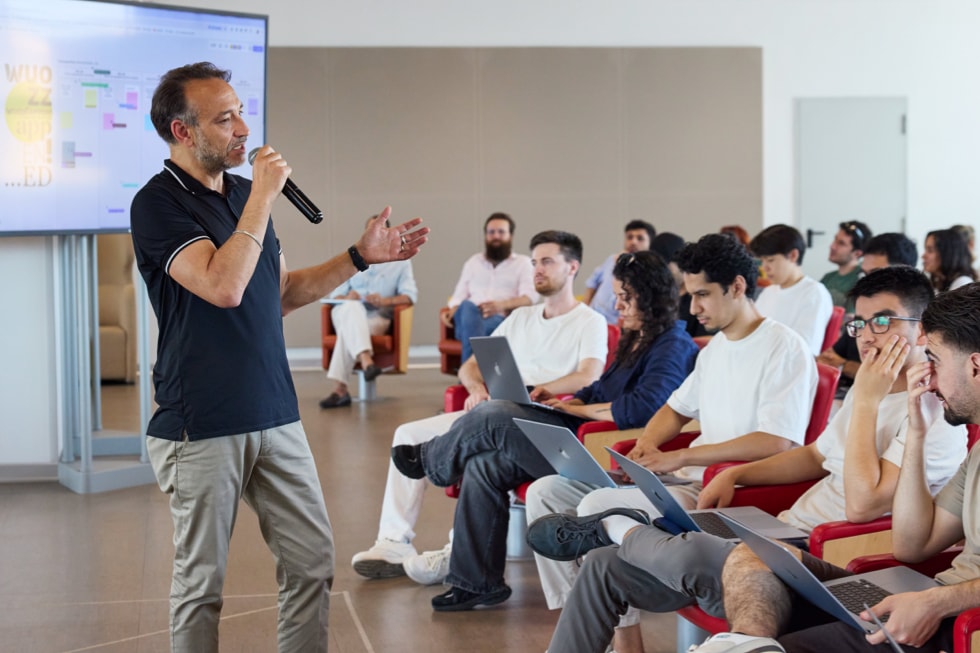 Docente che tiene una presentazione in un’aula piena di studenti alla Apple Developer Academy di Napoli.