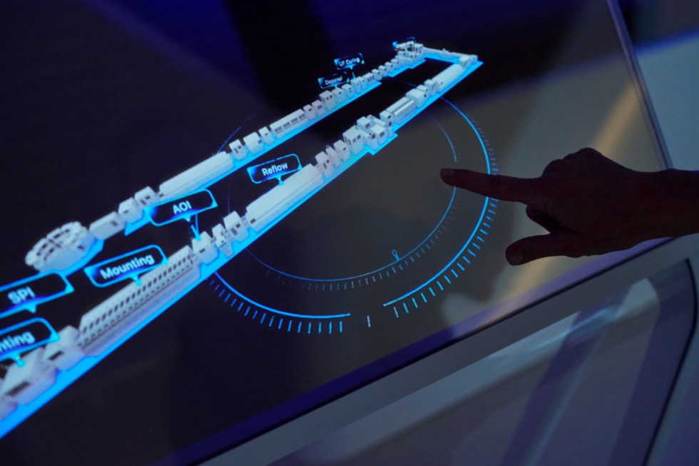 A hand is shown pointing to an interactive floor plan at Apple’s Advanced Manufacturing Center in Houston.