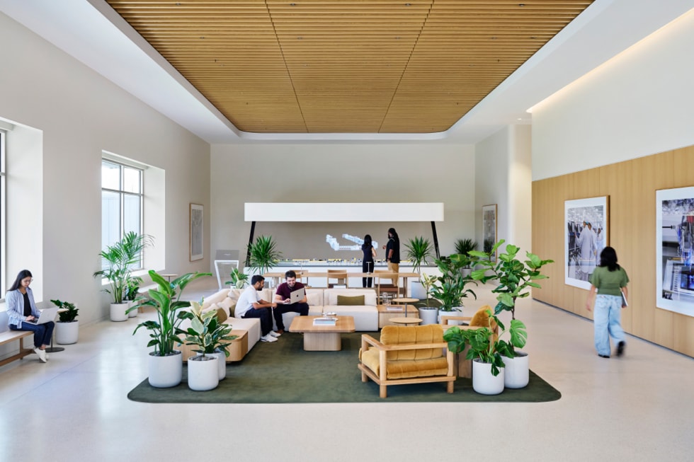 An interior shot of the Advanced Manufacturing Center in Houston shows various people seated and working on MacBook, walking, and looking at a holographic table.