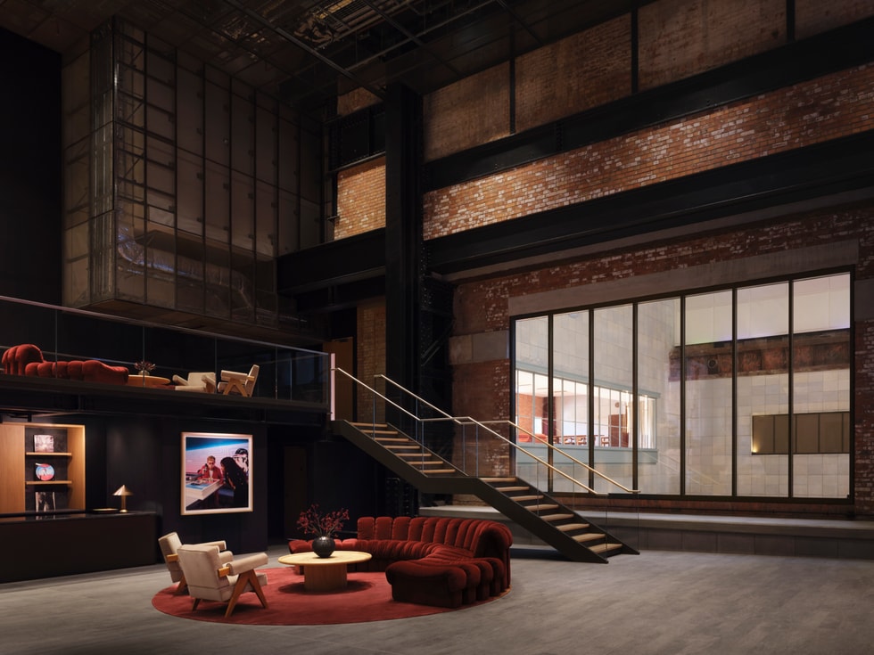 A comfortable foyer with a seating area, a large glass window, and a staircase inside Apple Music Hall.