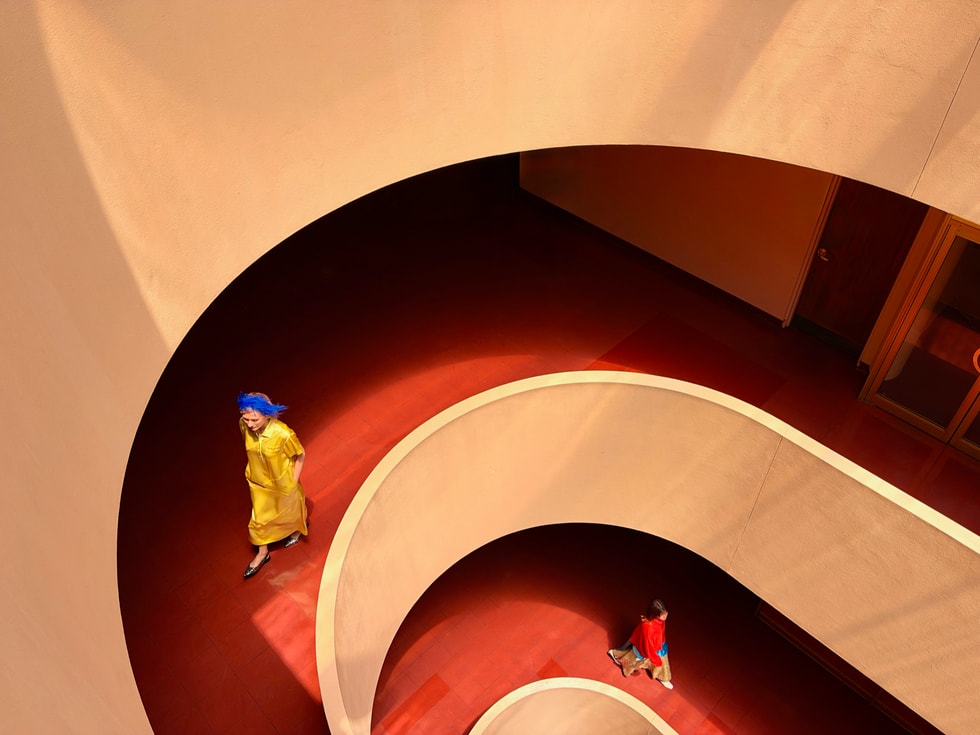 A person descends a spiral staircase indoors.