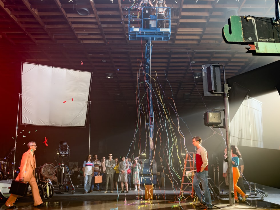 People are pictured walking on set while confetti falls from the ceiling.