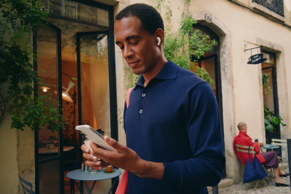 A user smiles while browsing on iPhone 17 outdoors.