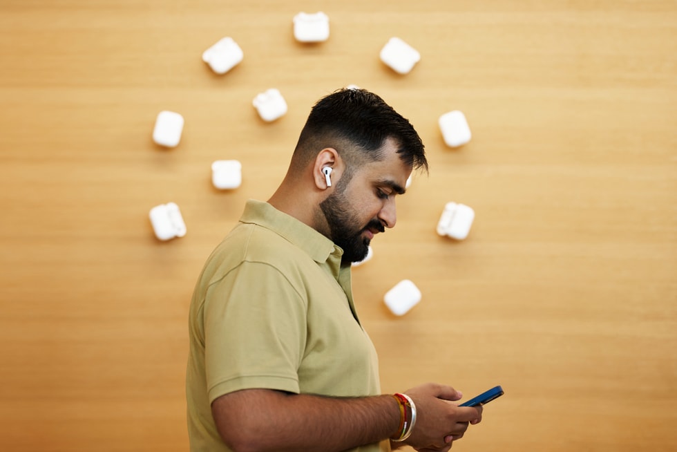 A customer is shown in profile trying out AirPods 5 and iPhone 18 Pro at Apple BKC.