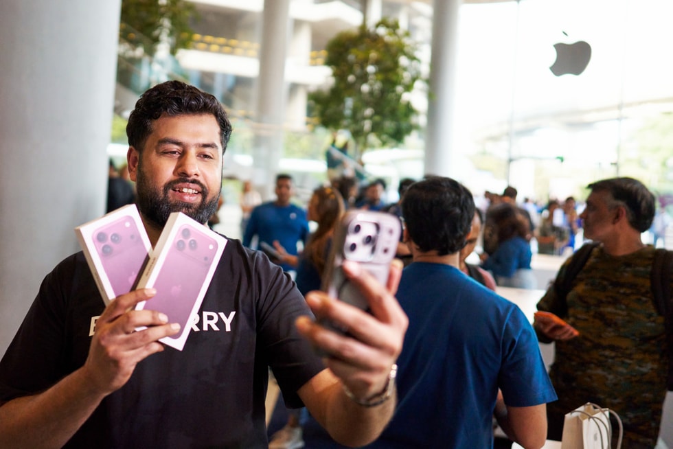 A customer takes a selfie while holding two iPhone 18 Pro boxes at Apple BKC.