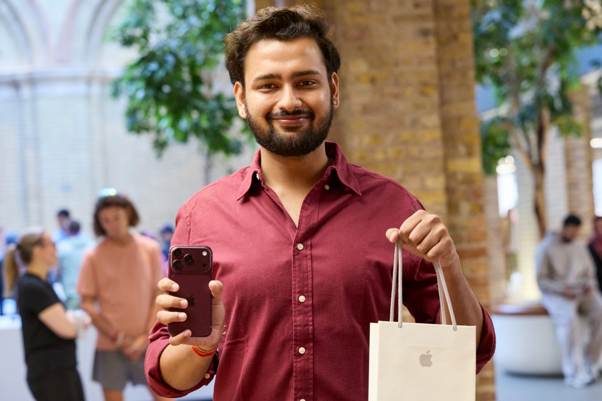 A customer holds up a recent purchase of the burgundy iPhone 18 Pro at Apple Covent Garden.