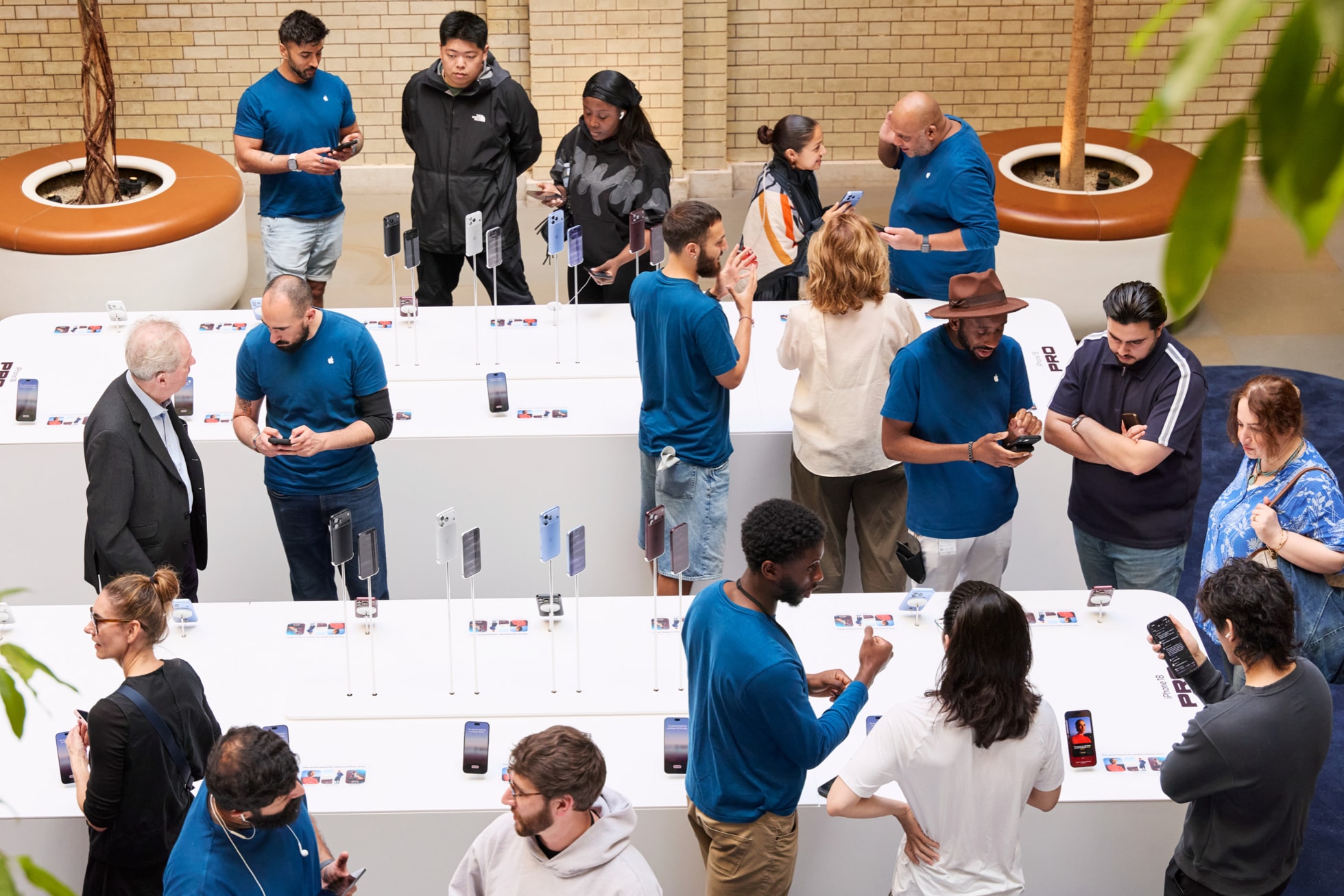 Team members assist customers at iPhone display tables at Apple Covent Garden.