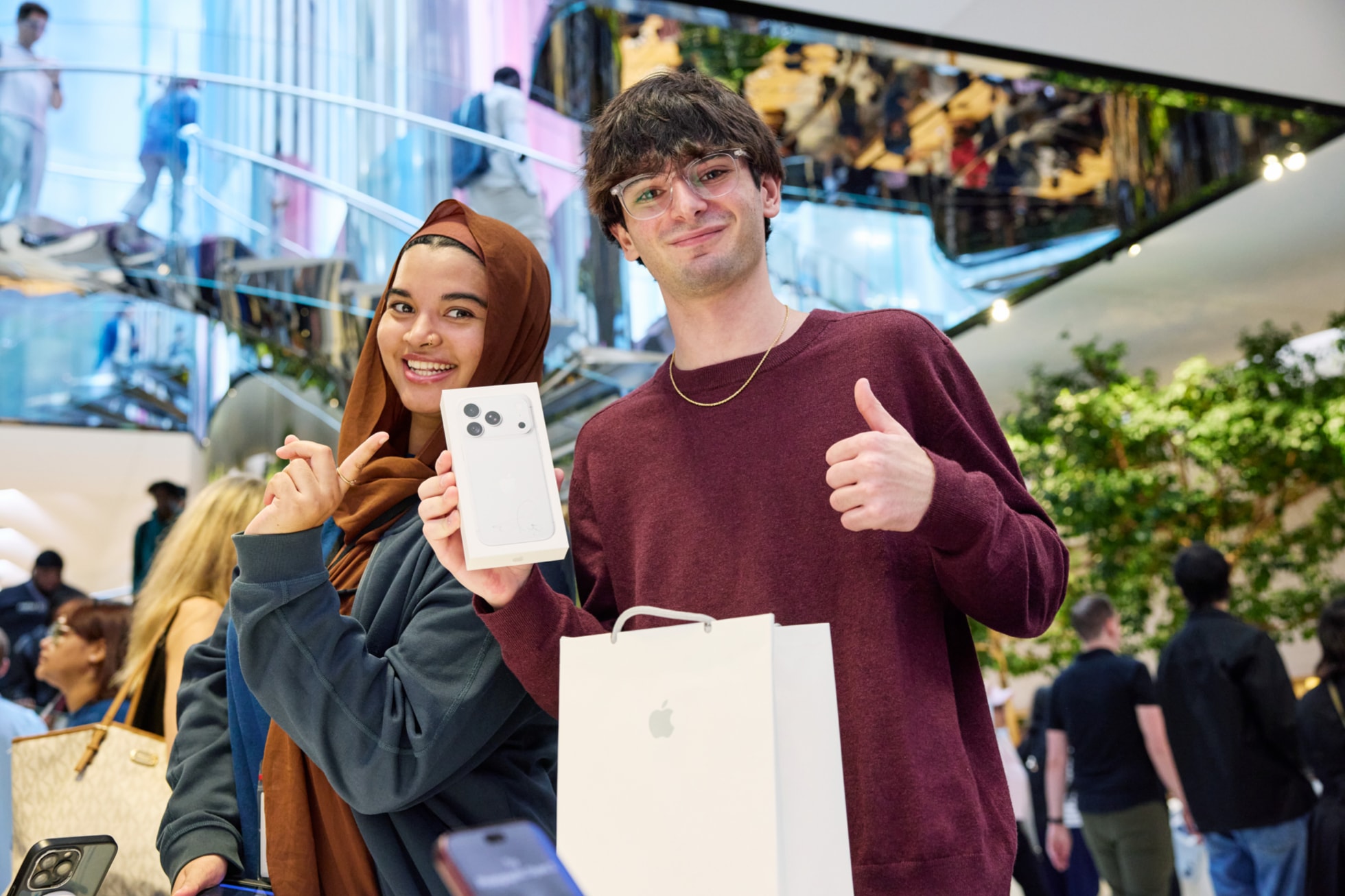 A customer gives a thumbs-up while holding up his iPhone 18 Pro purchase.