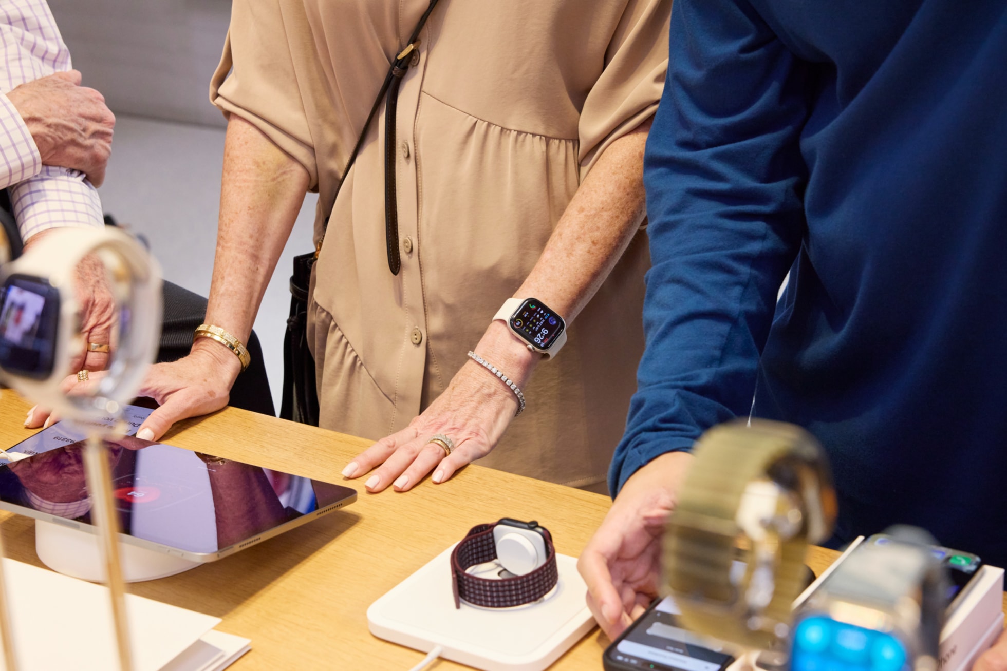 At an Apple Watch display table, customers try out Apple Watch models with iPad and iPhone at Apple Fifth Avenue.