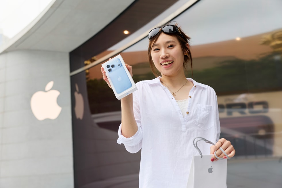 A customer holds up their new iPhone 18 Pro purchase outside Apple Jing’an.