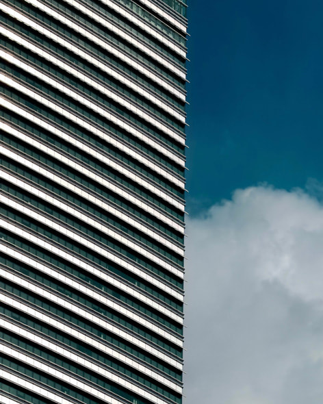 A close-up on a circular building that is part of twin skyscrapers in Kuala Lumpur, with taller towers rising up behind it.