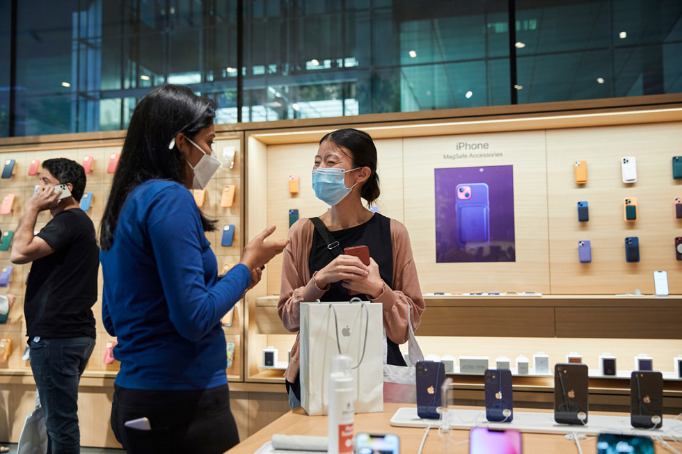 An Apple team member helping a customer inside Apple Al Maryah Island.